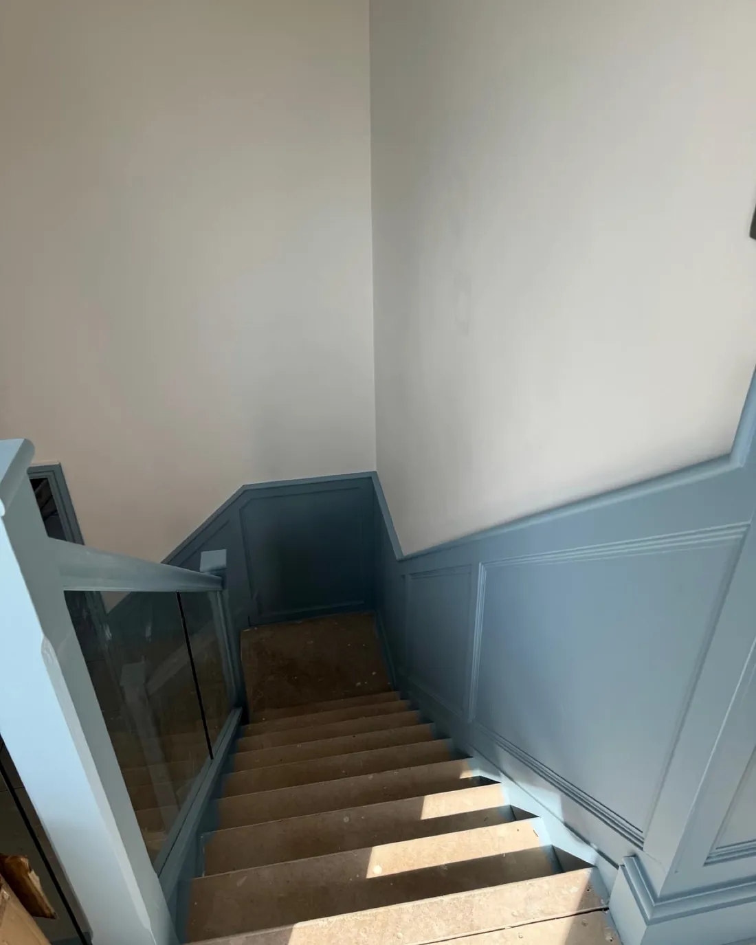 Stairwell with blue panelled walls and a glass balustrade