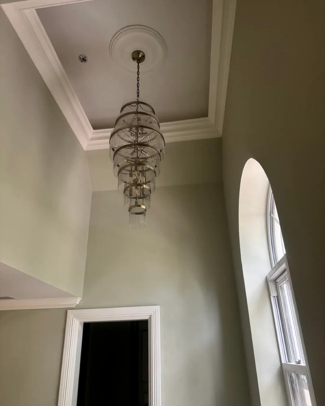 Stairwell with an arched window and a tiered glass chandelier