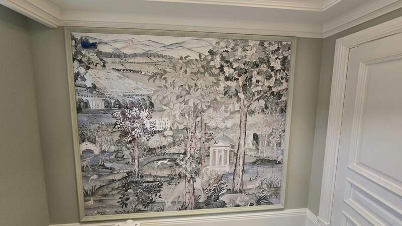 A landscape mural hung on a panelled wall